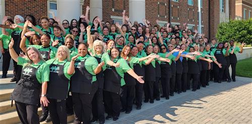 large group of women in matching green shirts and aprons